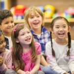 A multi-ethnic group of elementary age children are listening to their teacher read a storybook in class.